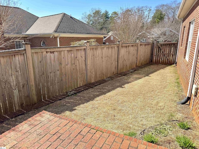 view of yard featuring a gate, a fenced backyard, and a patio