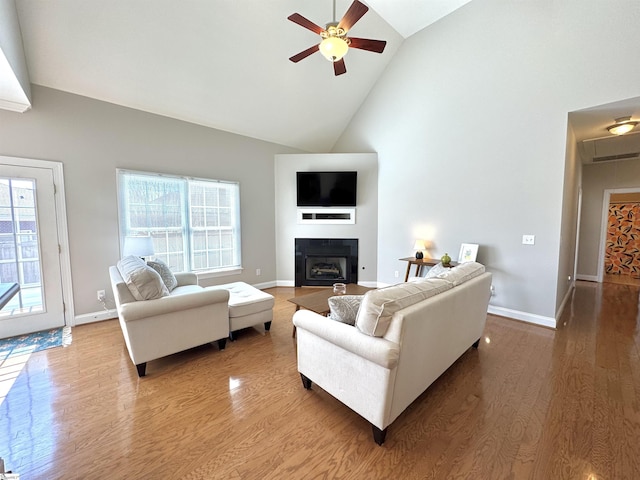 living area with ceiling fan, high vaulted ceiling, a fireplace, and wood finished floors