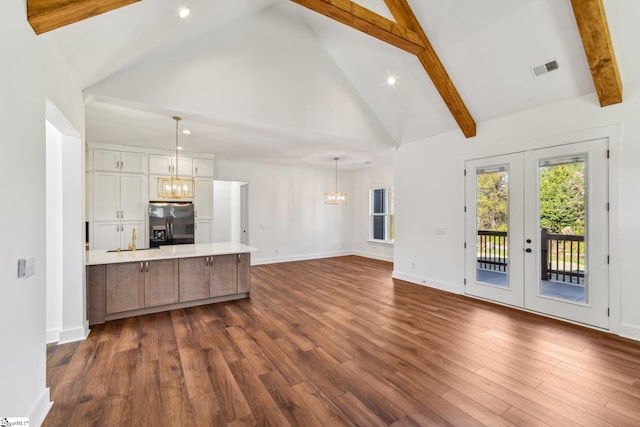 unfurnished living room with dark wood-type flooring, a notable chandelier, and beamed ceiling