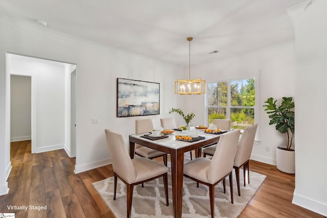 dining area featuring visible vents, baseboards, wood finished floors, an inviting chandelier, and crown molding