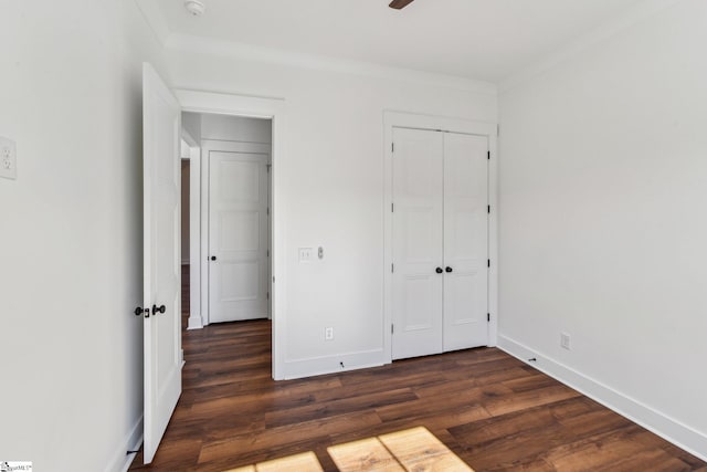 unfurnished bedroom with baseboards, dark wood-type flooring, a closet, and crown molding