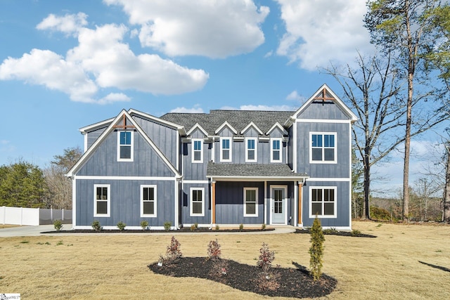 view of front of house featuring board and batten siding, roof with shingles, fence, and a front lawn