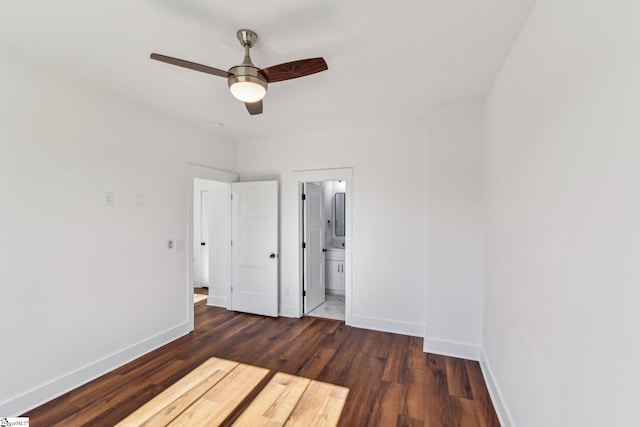 unfurnished bedroom with dark wood-style floors, ceiling fan, ensuite bathroom, and baseboards