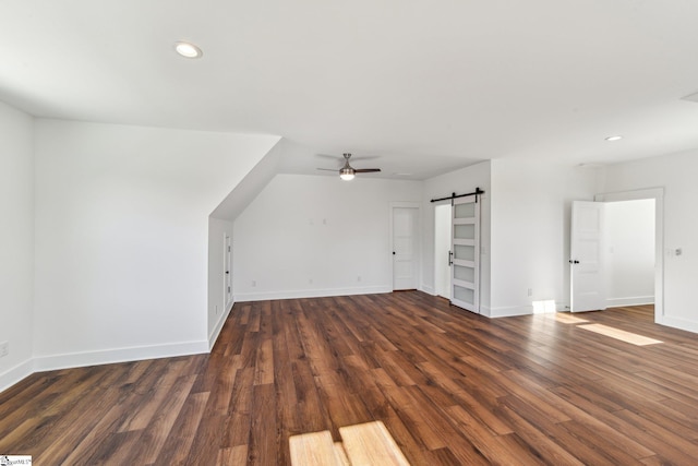 additional living space with a barn door, baseboards, dark wood-type flooring, and recessed lighting