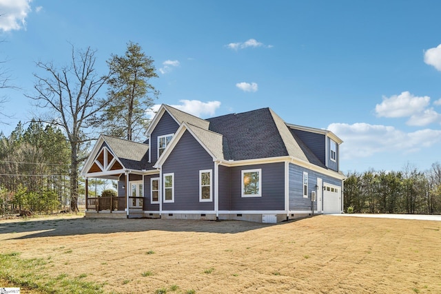 exterior space with roof with shingles, a yard, a porch, an attached garage, and crawl space