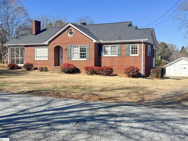 view of front of house featuring a front yard, roof with shingles, a chimney, and brick siding