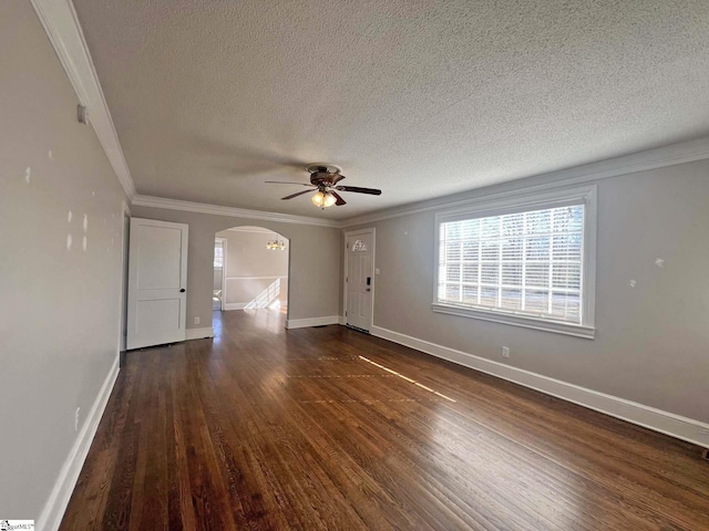 empty room with crown molding, arched walkways, dark wood finished floors, and baseboards