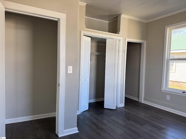 unfurnished bedroom with dark wood-type flooring, a closet, ornamental molding, and baseboards