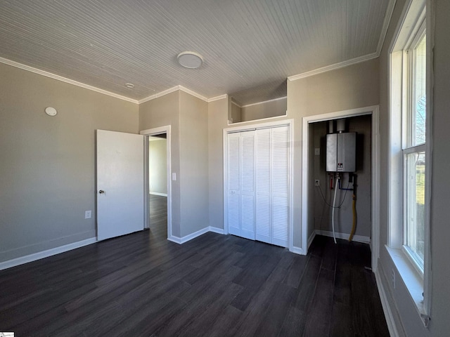 unfurnished bedroom with dark wood-style floors, crown molding, a closet, tankless water heater, and baseboards