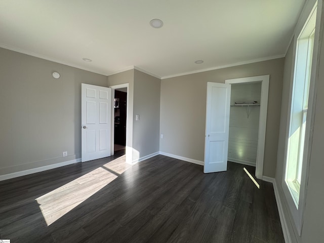 unfurnished bedroom featuring crown molding, dark wood-type flooring, a closet, and baseboards