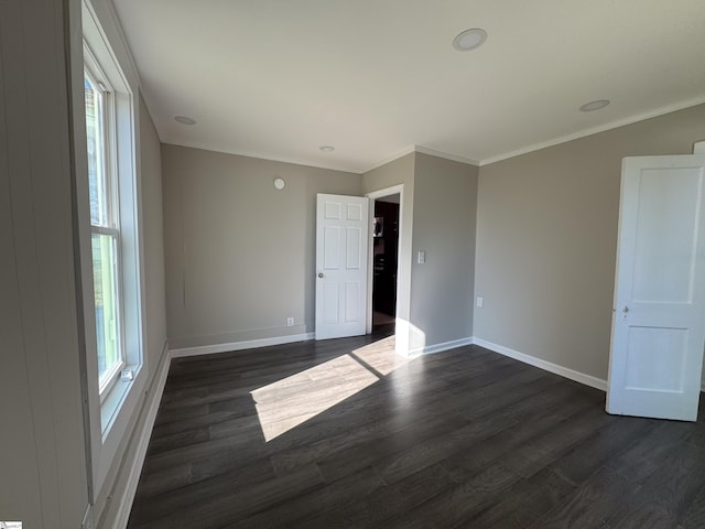 spare room with dark wood-style floors, baseboards, and crown molding