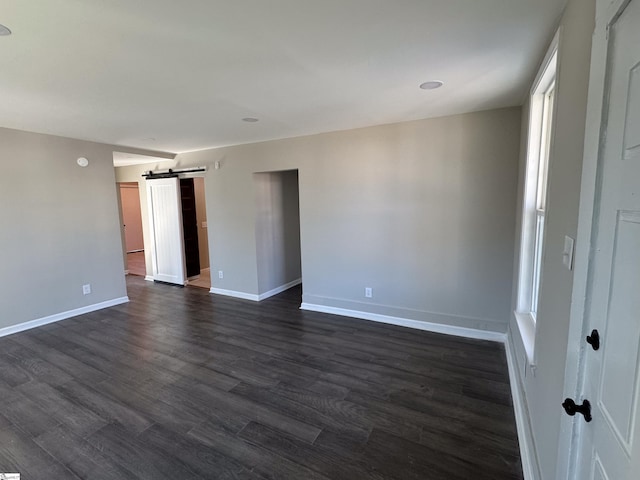 interior space with dark wood-style floors, a barn door, and baseboards