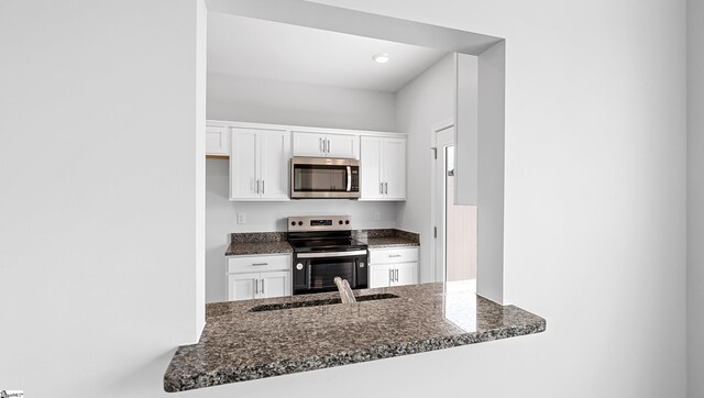 104 Sunriff Ct, Greer, SC 29651 - kitchen featuring appliances with stainless steel finishes, dark stone countertops, white cabinets, and a peninsula