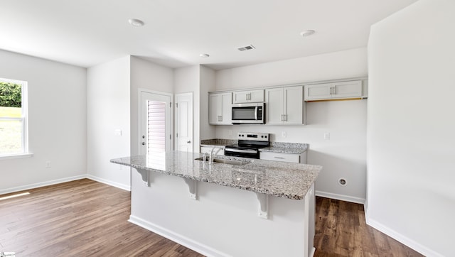 108 Sunriff Ct, Greer, SC 29651 - kitchen featuring stainless steel microwave, electric range oven, a kitchen breakfast bar, dark wood finished floors, and light stone countertops