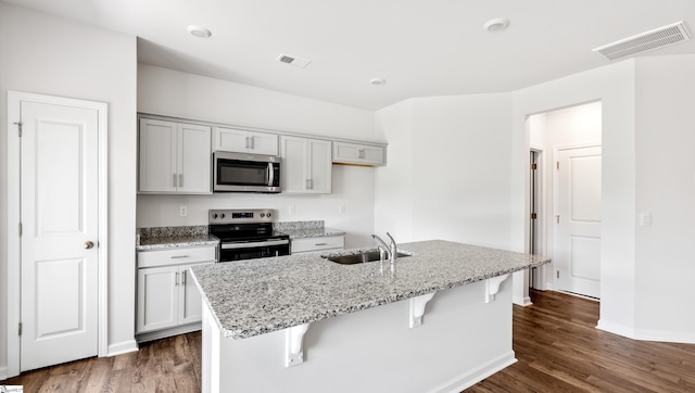 108 Sunriff Ct, Greer, SC 29651 - kitchen with stainless steel appliances, dark wood-style flooring, light stone counters, and a breakfast bar