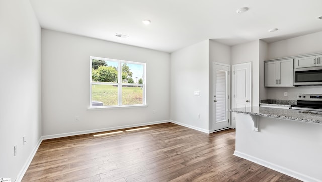 108 Sunriff Ct, Greer, SC 29651 - kitchen featuring appliances with stainless steel finishes, light stone counters, wood finished floors, a breakfast bar, and gray cabinetry