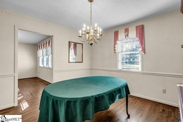 dining space featuring a notable chandelier, a textured ceiling, baseboards, and wood finished floors