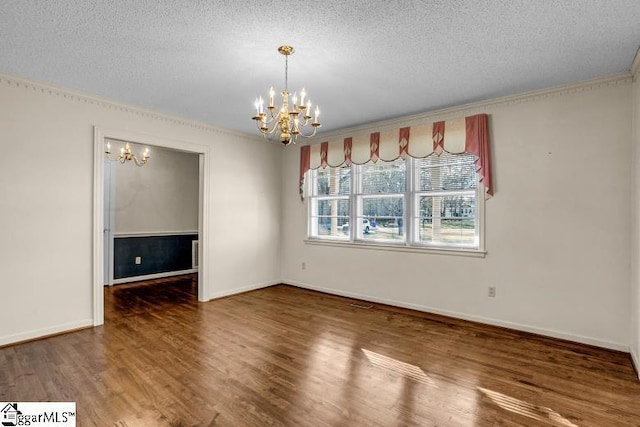 unfurnished dining area featuring dark wood-style floors, a textured ceiling, baseboards, and a notable chandelier