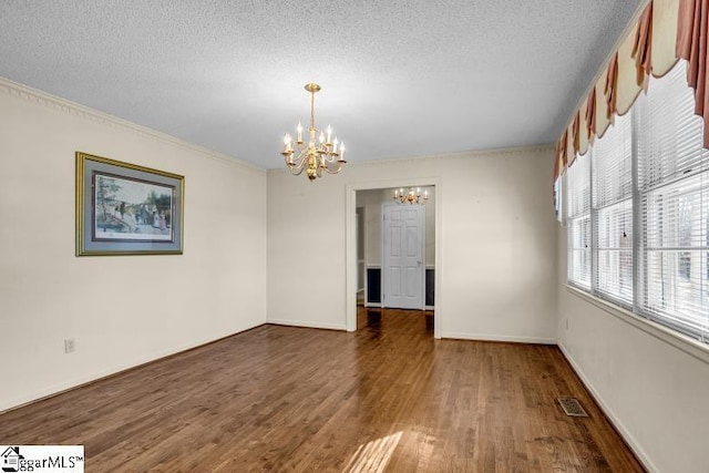 empty room with baseboards, visible vents, dark wood-style flooring, a textured ceiling, and a chandelier