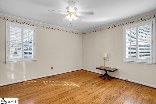 empty room with wood finished floors, a wealth of natural light, and crown molding