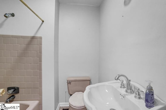 full bath featuring toilet, baseboards, and a sink