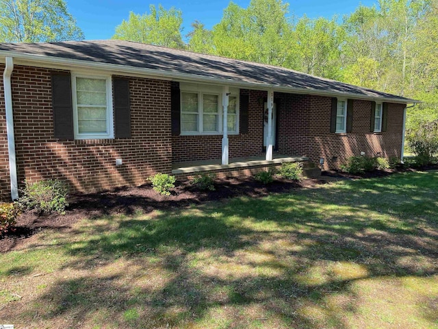 ranch-style house featuring a porch, a front yard, and brick siding