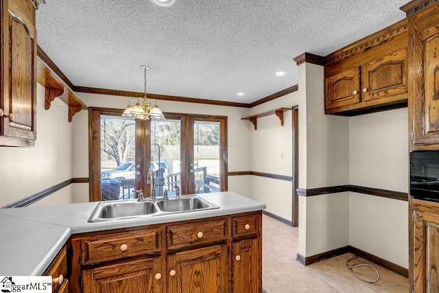 kitchen with a sink, baseboards, light countertops, hanging light fixtures, and brown cabinets