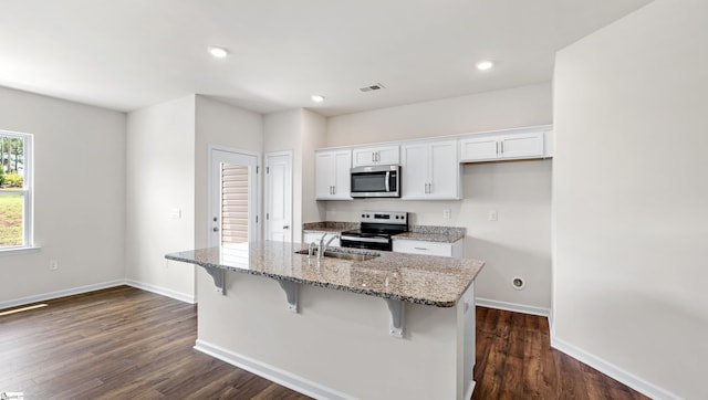 106 Sunriff Ct, Greer, SC 29651 - kitchen featuring electric range, stainless steel microwave, white cabinets, a center island with sink, and light stone countertops