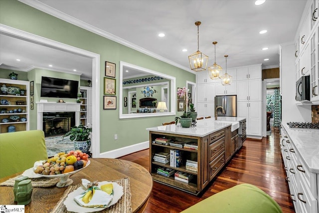 kitchen featuring a kitchen island with sink, stainless steel appliances, a sink, white cabinetry, and pendant lighting