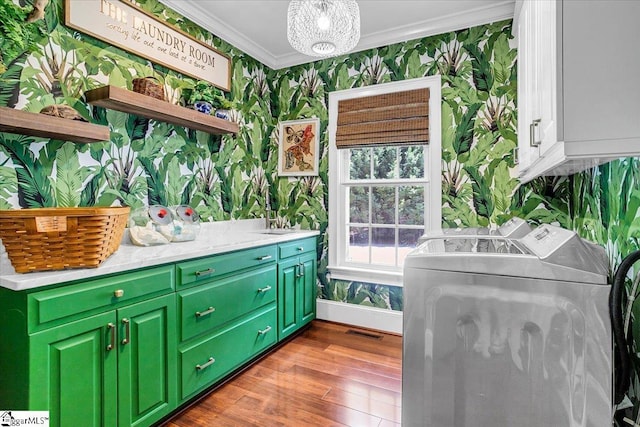 laundry area featuring visible vents, ornamental molding, cabinet space, washing machine and clothes dryer, and wallpapered walls