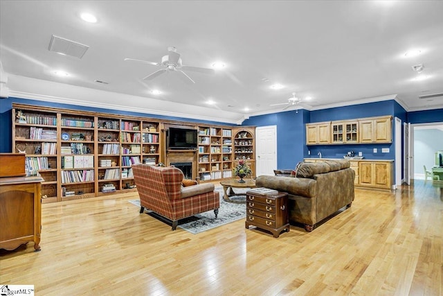 living area featuring ceiling fan, crown molding, light wood-type flooring, a fireplace, and recessed lighting