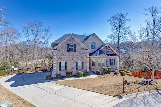 craftsman inspired home featuring concrete driveway, brick siding, and fence