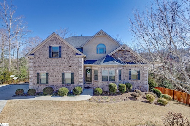 craftsman house featuring brick siding, a front yard, fence, and a shingled roof