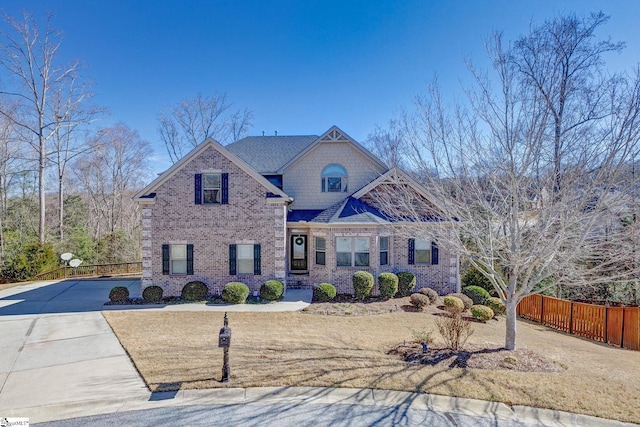 craftsman-style home featuring driveway, a front yard, fence, and brick siding