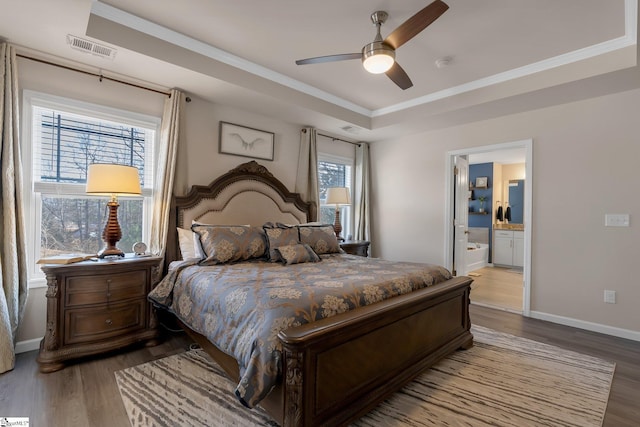 bedroom with light wood-type flooring, a tray ceiling, visible vents, and baseboards