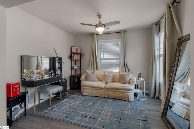 living area featuring dark wood-type flooring, baseboards, and a ceiling fan