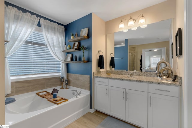 full bath featuring a stall shower, a garden tub, and vanity