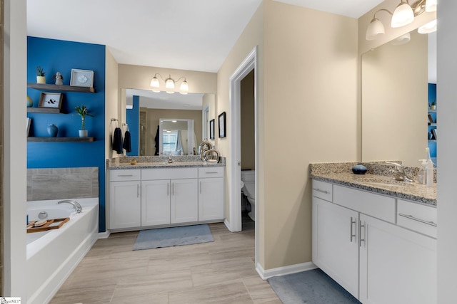 full bath featuring a garden tub, two vanities, toilet, a sink, and baseboards