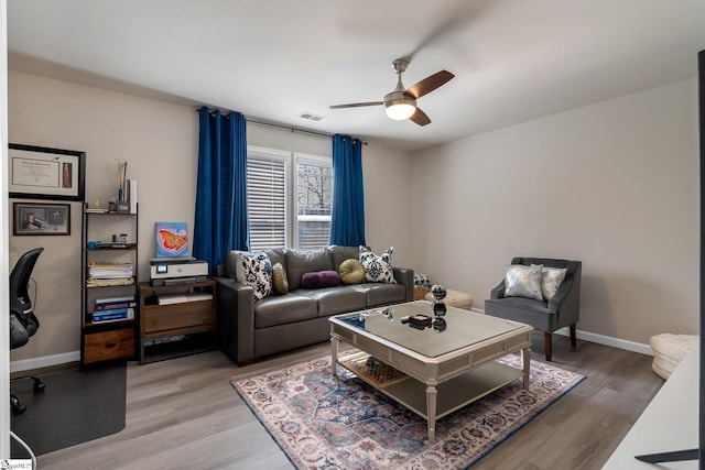 living area featuring a ceiling fan, wood finished floors, visible vents, and baseboards