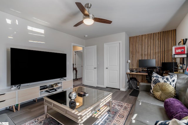 living area with dark wood finished floors, baseboards, and ceiling fan