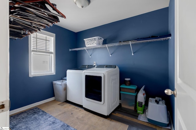 washroom featuring laundry area, washer and clothes dryer, wood finished floors, and baseboards