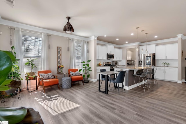 kitchen featuring a breakfast bar, a center island with sink, appliances with stainless steel finishes, and white cabinets