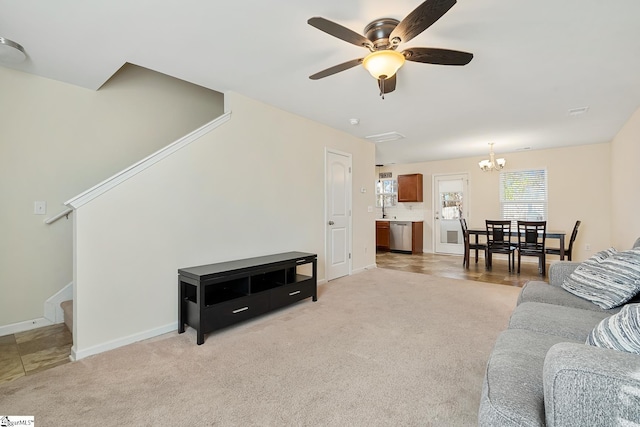 living room with light carpet, stairs, baseboards, and ceiling fan with notable chandelier