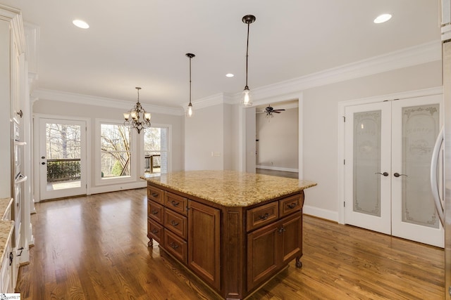 kitchen featuring dark wood-style flooring, light stone countertops, decorative light fixtures, and a center island