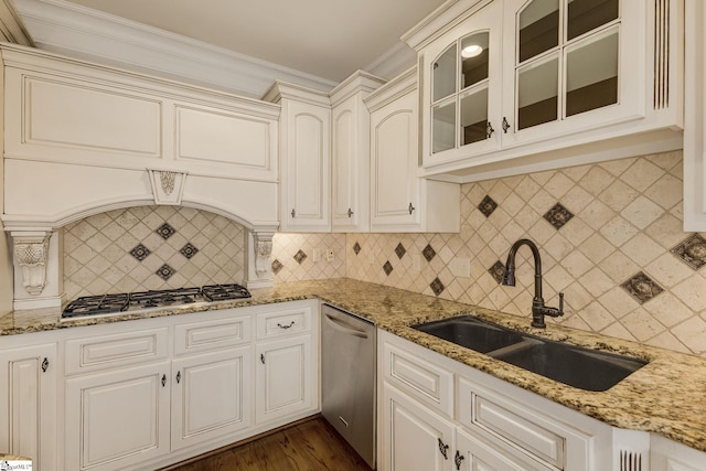 kitchen with decorative backsplash, glass insert cabinets, appliances with stainless steel finishes, light stone countertops, and a sink