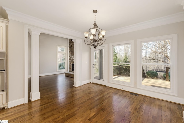 unfurnished dining area with ornamental molding, dark wood-style flooring, baseboards, and ornate columns