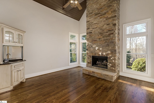 unfurnished living room featuring a healthy amount of sunlight, baseboards, dark wood finished floors, and a sink