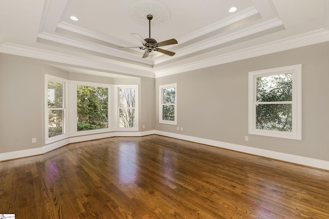 spare room with baseboards, visible vents, a raised ceiling, wood finished floors, and crown molding