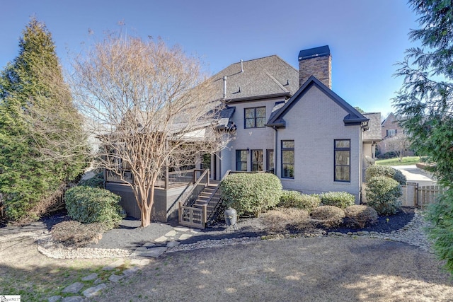 exterior space with a chimney, brick siding, and stairway