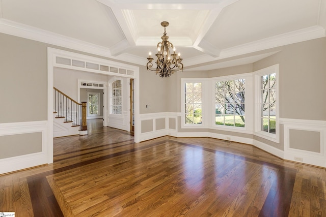 spare room featuring coffered ceiling, stairway, wainscoting, and dark wood finished floors